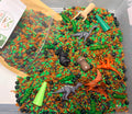 Dino Dig dinosaur sensory play kit with colourful filler, dinosaur figures and a bamboo scoop.